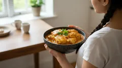 Žena drží misku s domácím jídlem, guláš s knedlíky, posezení v kuchyni