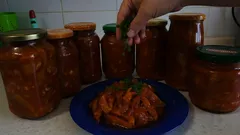 Domácí zavařenina v zavařovacích sklenicích a zeleninový pokrm na modrém talíři.