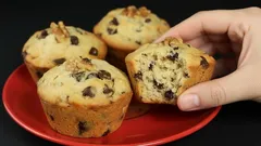 Čokoládové muffiny na červeném talíři, jedna muffina rozkrojená v ruce