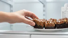 Ruka bere čokoládový zákusek z talíře v lednici